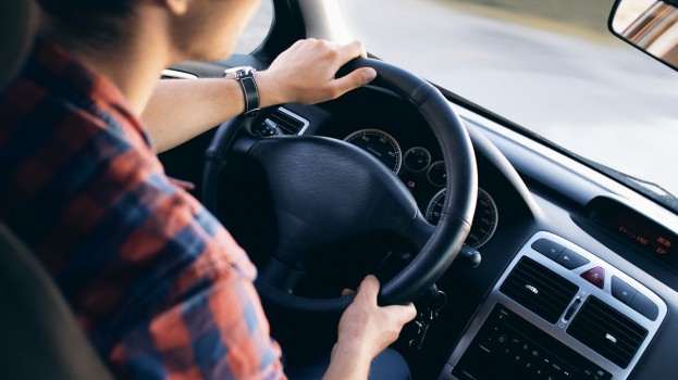 Young driver in his shirt in a nice modern car in motion